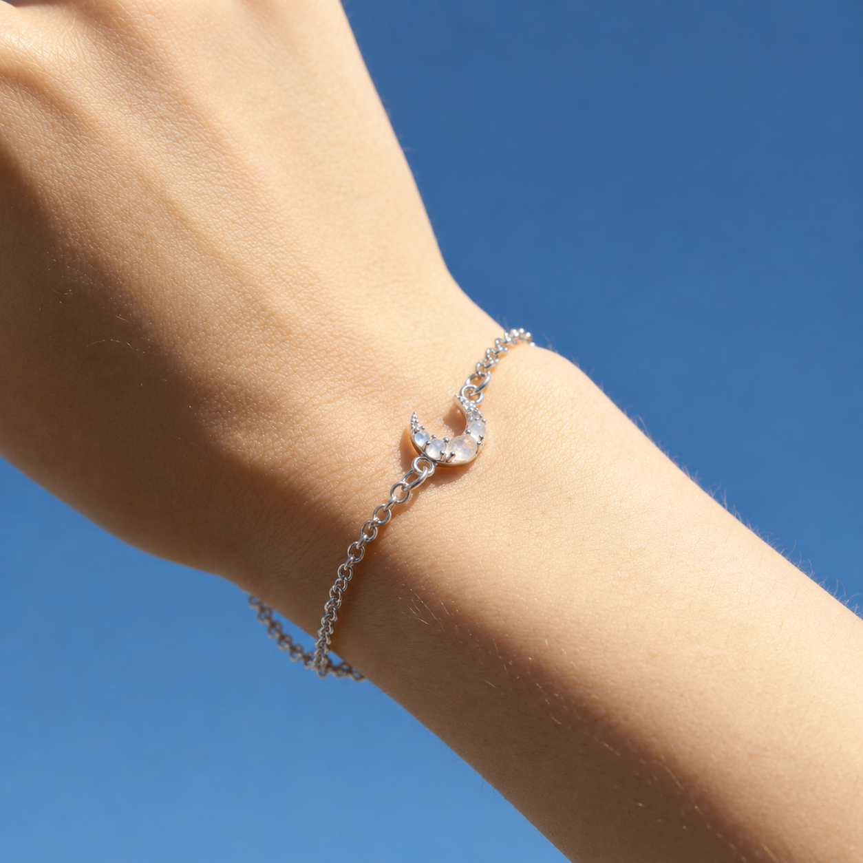 Zilveren maanarmband tegen blauwe lucht
